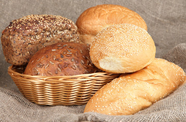 Baked bread in wicker basket on burlap background