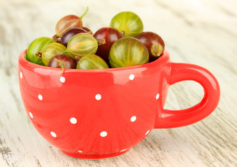 Fresh gooseberries in cup on table close-up