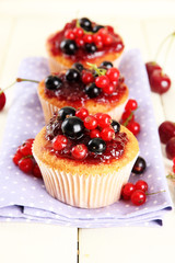 Tasty muffins with berries on white wooden table