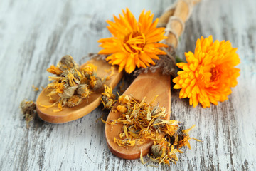 Fresh and dried calendula flowers on wooden background