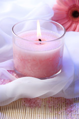 Beautiful candle with flower on white cloth, close up