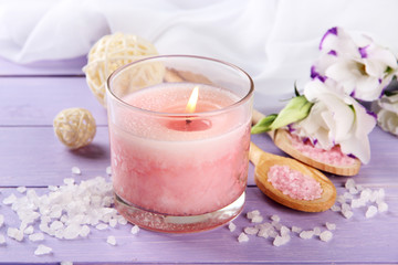 Beautiful pink candle with flowers on purple wooden background
