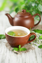Teapot and cup of herbal tea with fresh mint flowers
