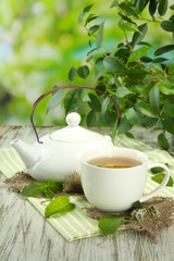 Teapot and cup of herbal tea with fresh mint on wooden table