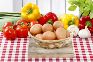 Stack of eggs, fresh vegetables in the background