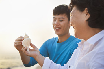 Grandmother and Grandson Looking At Seashell