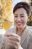 Mature Woman Holding Yellow Ginkgo Leaf