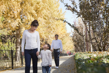 Obraz premium Grandparents and Granddaughter Walking in the Park