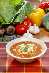 Tomato soup and fresh raw vegetables in the background. Wooden r