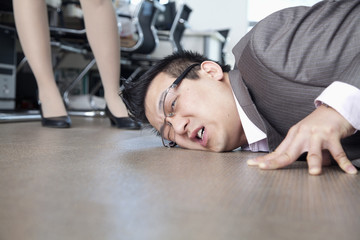 Fototapeta na wymiar Businessman with face on the floor, coworker standing by him