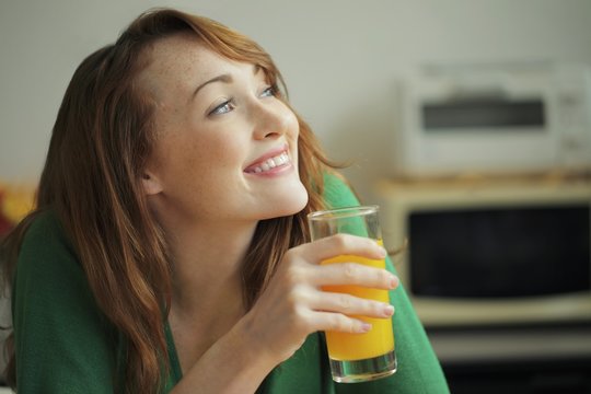 A young woman holding a glass of orange juice