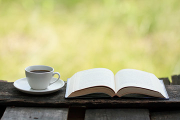 Cup of coffee and a book on a wooden table