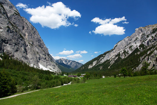 summer landscape in the Alps with green grass, road and clouds