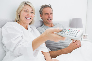 Obraz premium Happy couple watching tv in bed