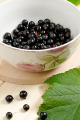 Black currants in a bowl on a wooden table
