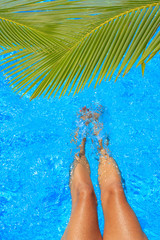 women legs splashing in tropical swimming pool