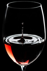 Rotwein tropft in ein Rotweinglas