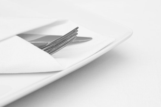 Place setting, white plate with cutlery and white napkin