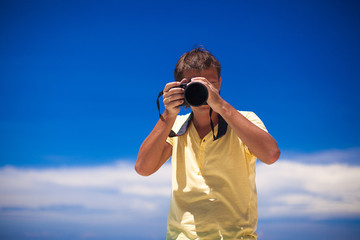 In front of the camera young man with camera in hands background