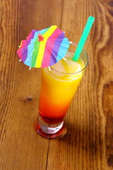 Red, yellow cocktail with lemon, straw and umbrella deco
