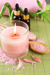 Beautiful spa setting with pink candle on bamboo mat