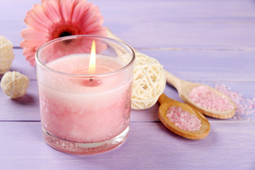 Beautiful pink candle with flower on purple wooden background