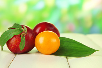 Ripe plums on wooden table on natural background