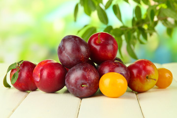 Ripe plums on wooden table on natural background
