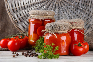 Tasty canned and fresh tomatoes on wooden table