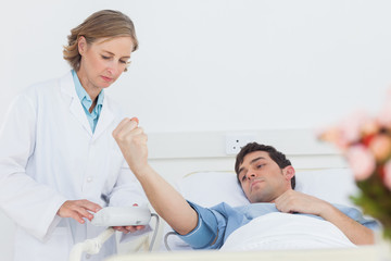 Woman doctor taking the blood pressure of male patient