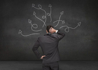 Doubtful businessman looking at arrows