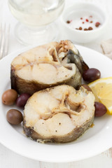 boiled fish with olives on the plate