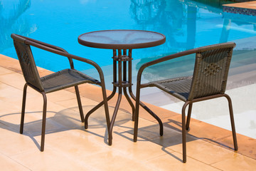 Table with chairs standing against the swimming pool