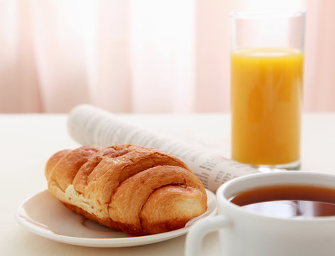 Glass of refreshing orange fruit juice and croissant