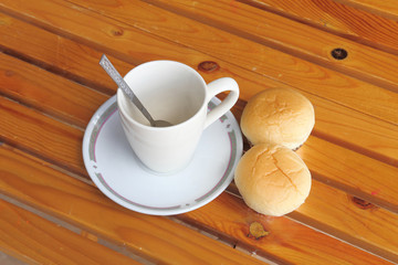 Bread with empty cup of coffee on the yellow wood table