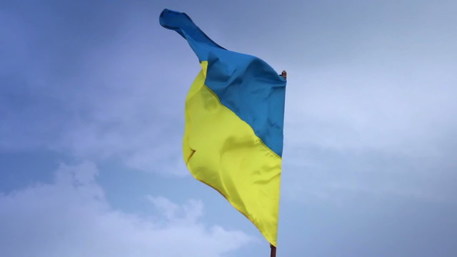 Ukrainian national flag waving on flagpole in blue sky. Ukraine