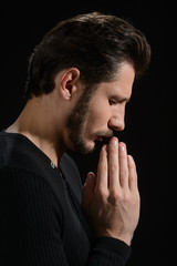 The power of prayer. Side view of bearded man praying and holdin