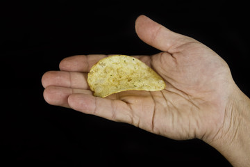 Hand holding one potato chip