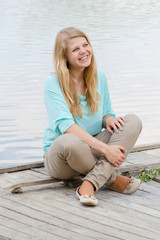 Fototapeta na wymiar Young woman sitting on pier and smiling