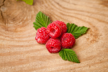 ripe raspberries with leafs on the wood