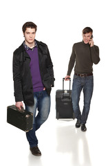 Two guys in full length traveling with suitcases