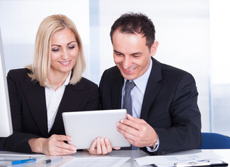 Businessman And Businesswoman Looking At Digital Tablet