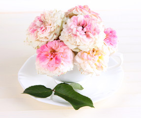 Roses in cup on wooden background