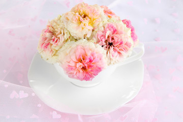 Fototapeta na wymiar Roses in cup on light pink background