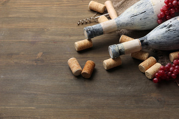 Old bottles of wine, grapes and corks on wooden background