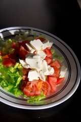 Vegetable salad with cheese on dark wooden table