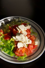 Vegetable salad with cheese on dark wooden table
