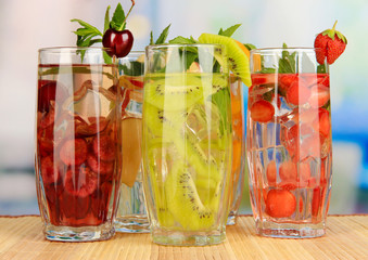 Glasses of fruit drinks with ice cubes on table in cafe