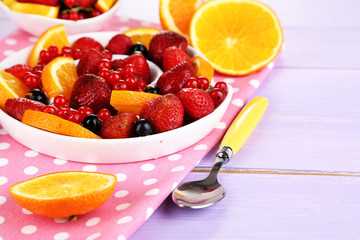 Useful fruit salad in plate on wooden table close-up