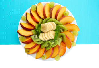 Assortment of sliced fruits on plate, isolated on white